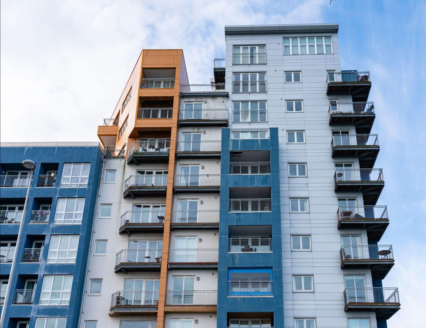 A blue and orange apartment building with balconies.